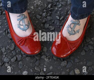 Gros plan des pieds femelles avec des tatouages d'ancre portant des plats de ballet brevetés . Banque D'Images