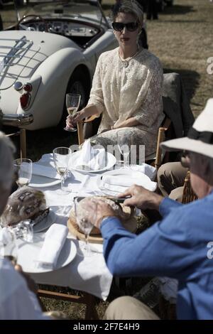 Une femme et un homme ayant un pique-nique à Goodwood Revival entouré de voitures classiques , Chichester, West Sussex, Angleterre Banque D'Images