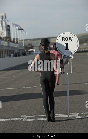 Jeunes filles avec des panneaux indiquant la rangée de départ à la réunion de renouveau de Goodwood 2012. Banque D'Images