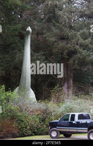 Une statue de brontosaurus semble sortir de la forêt à côté d'un camion dans les jardins préhistoriques de Port Orford, Oregon. Banque D'Images