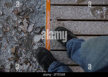 Regarder vers le bas vers les pieds dans les chaussures noires et les jeans debout sur une couche légère de neige. Banque D'Images