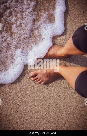 Mousse de mer se lavant doucement sur les pieds d'un womans sur un Journée ensoleillée à Hawaï Banque D'Images