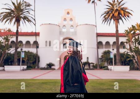 Femme portant une robe de remise des diplômes devant le bâtiment de l'université. Banque D'Images
