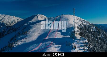 Panorama aérien de la piste de ski de Krvavec en Slovénie, tour ou antenne TV visible et aussi un parcours de ski entre la clôture rouge. Banque D'Images