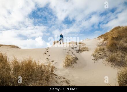 Femme marchant sur les dunes de sable en hiver avec le ciel bleu et les nuages Banque D'Images