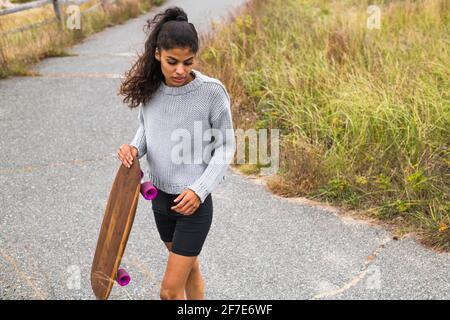 Jeune femme skate pieds nus le jour couvert Banque D'Images