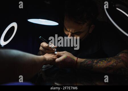 Manucuriste homme appliquant de la résine aux ongles d'un client Banque D'Images