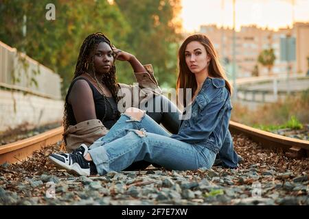 Deux jeunes femmes multiethniques posent et regardent la caméra au coucher du soleil Banque D'Images