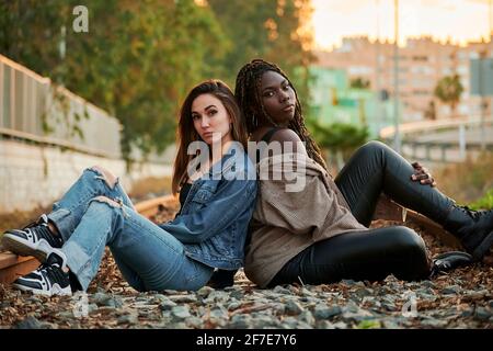 Deux jeunes femmes multiethniques posent et regardent la caméra au coucher du soleil Banque D'Images