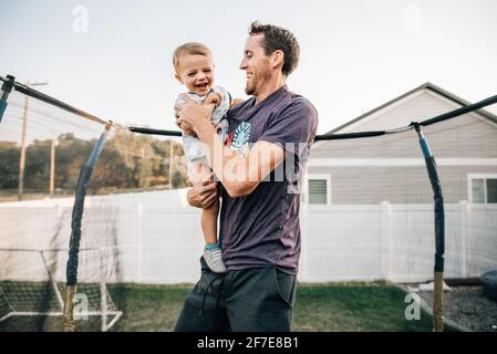 Papa rit sur le trampoline avec son tout-petit Banque D'Images