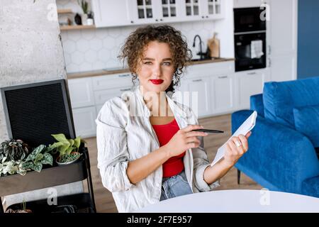 Portrait d'une femme d'affaires confiante et élégante prend des notes, regarde l'appareil photo, sourit. Jeune femme indépendante ou étudiante réussie à distance Banque D'Images