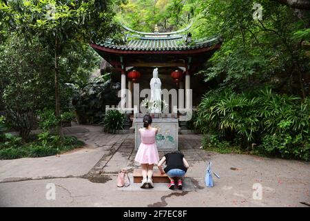 Femme priant devant une statue blanche de Guanyin. À l'intérieur du parc du temple de Nanputuo. Banque D'Images