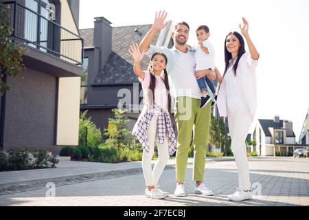 Photo pleine grandeur de jeunes heureux positif souriant famille agitant les mains saluent en disant bonjour se promener à l'extérieur Banque D'Images