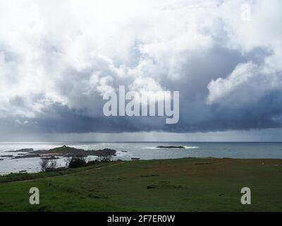 Des nuages gris orageux planant de manière inquiétante au-dessus de la mer. Pluie tombant dans la distance Banque D'Images