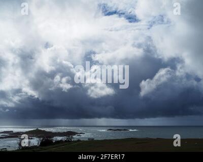 Tempête en mer, nuages gris sombres et dramatiques, planant de manière inquiétante au-dessus et projetant des ombres sur l'océan, pluie tombant au loin Banque D'Images