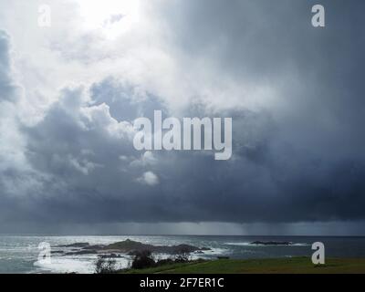 Vue de nuages gris de tempête, de pluie, planant de manière sinistre au-dessus et jetant des ombres sur la mer sombre. Banque D'Images