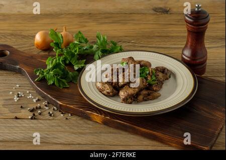 Foie de poulet cuit avec oignon sur une assiette servi sur un bureau en bois. Style rustique. Banque D'Images