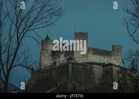 Forteresse historique Hohensalzburg ou festung dans la soirée coucher du soleil vue à travers les arbres à une heure bleue sur une soirée froide de novembre. Bleu riche aro Banque D'Images