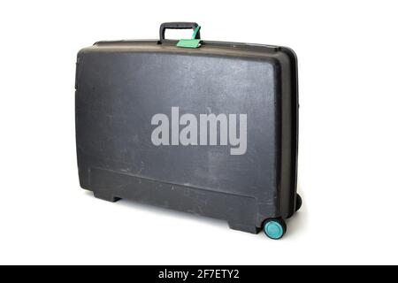 Valise en plastique de style ancien avec deux roues, poignée et étiquette verte isolée sur blanc. Valise assez usée de couleur grise et roues vertes. Banque D'Images