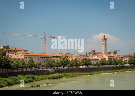 Vue sur la basilique de San Zeno Maggiore à Vérone au soleil surplombant la rivière Adige avec pierres et herbe sur la rive de la rivière. Romantique picuture de Banque D'Images