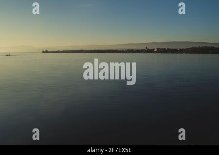 Belle soirée photo du lac Léman près de Lausanne, avec soleil juste au-dessus de l'horizon et longue exposition à l'eau. Banque D'Images