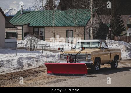 Un pick-up plus ancien avec chasse-neige rouge monté à l'avant. Banque D'Images