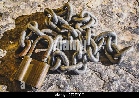 Un cadenas doré et une chaîne argentée montrant des signes d'usure dans un bacille rocheux. Banque D'Images