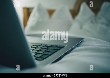 Vue détaillée d'un clavier d'ordinateur portable installé sur un lit dans la chambre d'hôtel. Chambre d'hôtel d'époque avec ordinateur portable sur la feuille. Concept de réservation d'hôtel en ligne. Banque D'Images