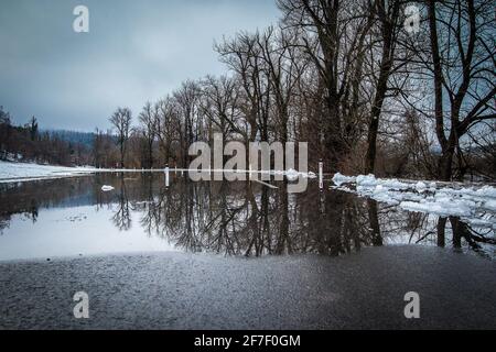 Route inondée d'eau en raison de la fonte de la neige. Les piliers de la route sont vus hors de l'eau sur une surface de route, Banque D'Images