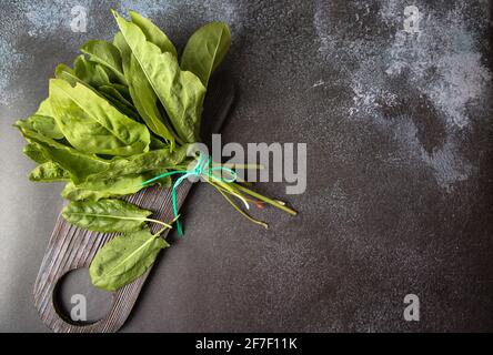 Feuilles de sorrel frais, un bouquet d'épinards sur un fond sombre. Des verts pour la soupe printanière de légumes verts et de salade. Banque D'Images