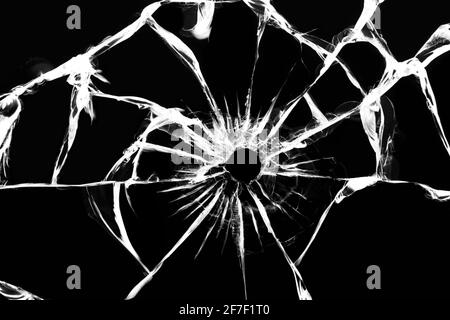 Verre endommagé présentant des fissures, fissures dans le verre résultant de la grenaille. Fenêtre cassée, texture sur fond noir Banque D'Images