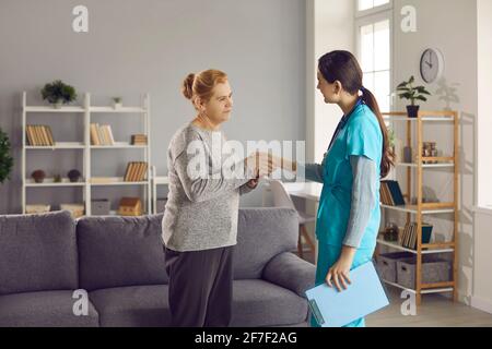 Une patiente âgée se secouant la main avec un jeune médecin, la remerciant de assistance professionnelle Banque D'Images