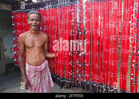 Sari Making Artisan debout près des fils colorés de teint dans le village de Muhulia de Cuttack district d'Odisha, Inde Banque D'Images