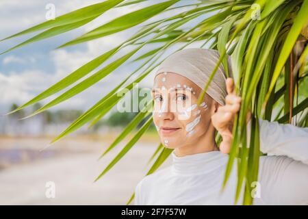 Kundalini yoga femme en vêtements blancs et turban pratique le yoga kundalini sur le fond de la mer, des montagnes et du coucher du soleil. Peinture de visage de combat Banque D'Images