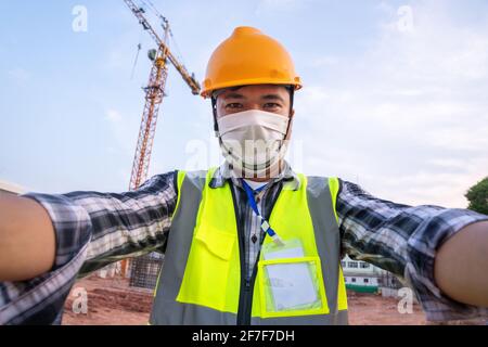 Portrait Selfie de l'ingénieur portant un EPI et un masque de protection virus corona ou Covid19 travaillant sur le chantier Banque D'Images