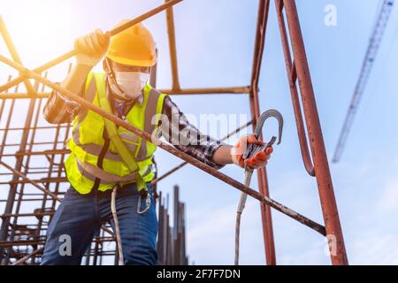 Travailleur travaillant en hauteur sur un chantier de construction. Dispositif antichute pour travailleur avec crochets pour harnais de sécurité sur le système sélectif Banque D'Images