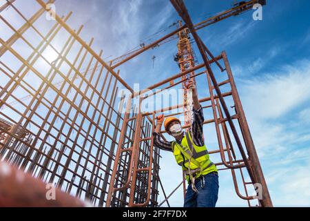 Travailleur asiatique travaillant sur la structure en acier à hauteur équipement constructif sur le chantier de construction. Dispositif antichute pour travailleur avec crochets pour la sécurité b Banque D'Images