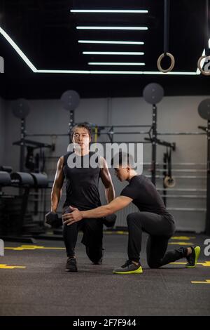 Homme mature s'entraîner avec un entraîneur personnel à la salle de gym Banque D'Images