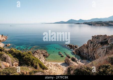 Une petite plage de galets et une mer Méditerranée translucide sur le Côte de la Revellata en Balagne, Corse Avec la citadelle de Calvi dans le Banque D'Images