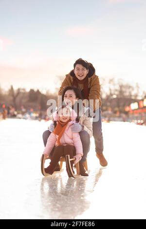 Bonne jeune famille en traîneau à l'extérieur Banque D'Images