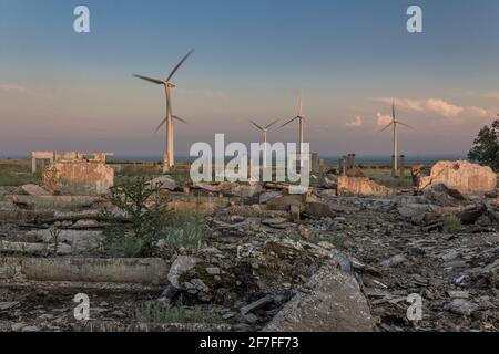 Les ruines d'une ferme de l'époque soviétique contre le toile de fond des éoliennes modernes Banque D'Images