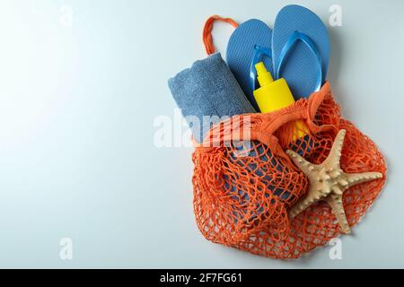 Sac avec crème solaire, tongs, serviette et étoiles de mer sur fond blanc Banque D'Images