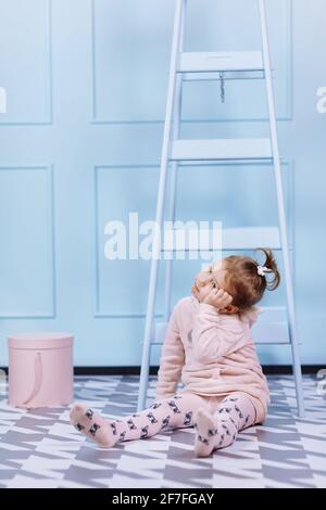 Souriant belle petite fille en costume rose licorne est souriant et s'amuser sur un fond de mur bleu. Enfance heureuse Banque D'Images