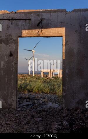 Les ruines d'une ferme de l'époque soviétique contre le toile de fond des éoliennes modernes Banque D'Images