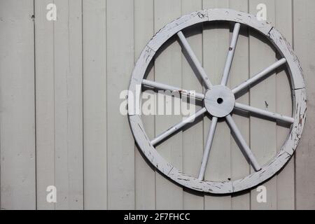 une ancienne roue de wagon montée sur un mur en bois blanc Banque D'Images