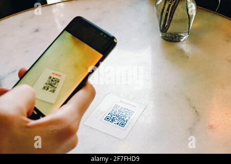 Homme scannant le code QR avec un téléphone portable au restaurant. Banque D'Images