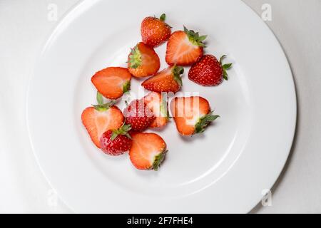 Fraises coupées en deux sur une assiette blanche. Vue de dessus. Fraises Banque D'Images