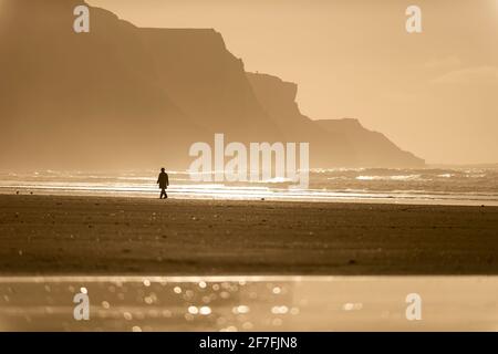 Personne marchant le long de la plage dans la lumière du soleil du soir, Rhossili, Gower Peninsula, Swansea, pays de Galles, Royaume-Uni, Europe Banque D'Images