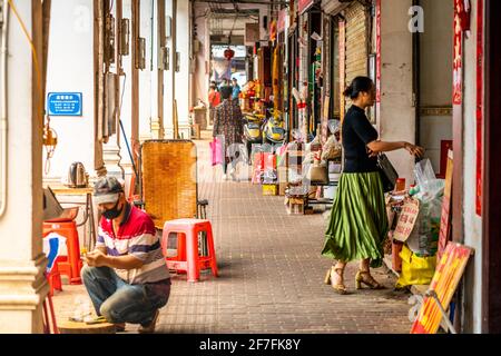 Haikou Chine , 21 mars 2021 : scène de la vie quotidienne sous la rue piétonne d'arcade de la vieille ville de Qilou avec des gens et des boutiques dans Haikou Hainan Chine Banque D'Images