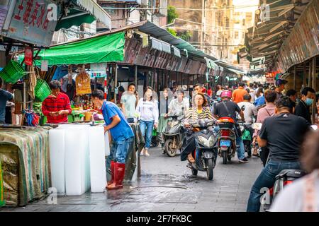 Haikou Chine , 21 mars 2021 : vue sur l'allée du marché de Dongmen avec des personnes sur scooter et des étals, y compris le magasin de blocs de glace dans la vieille ville de Haikou Hainan Chine Banque D'Images